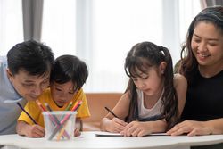 Asian parents helping kids to do homework at home