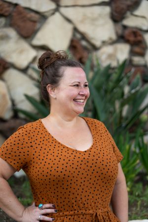 Happy woman smiling and looking away from camera outside in front of stone wall