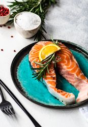 Salmon fish with rosemary and lemon on counter with copy space