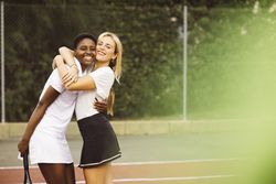 Portrait of two happy women in a tennis court