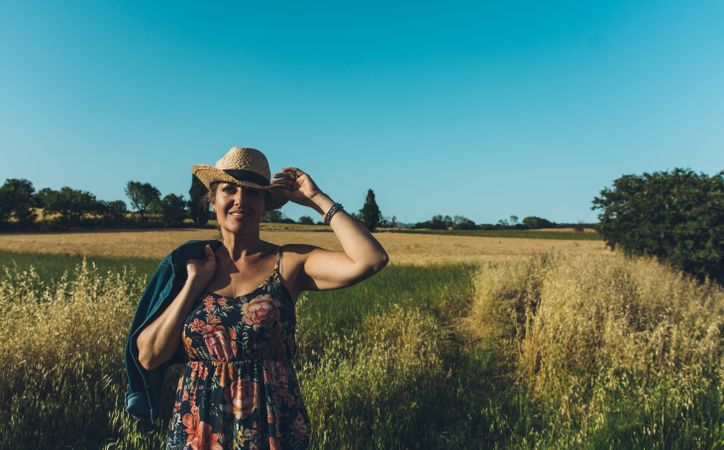 Female farmer with hat looking at her wheat crop.