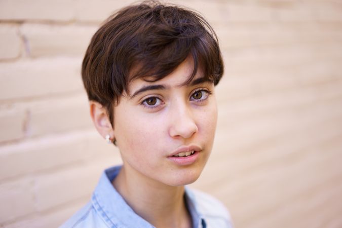 A Portrait of a Young Person with Short Hair Set Against a Soft and Gentle Background