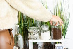 Unrecognizable person hand picking up a glass jar full of coffee