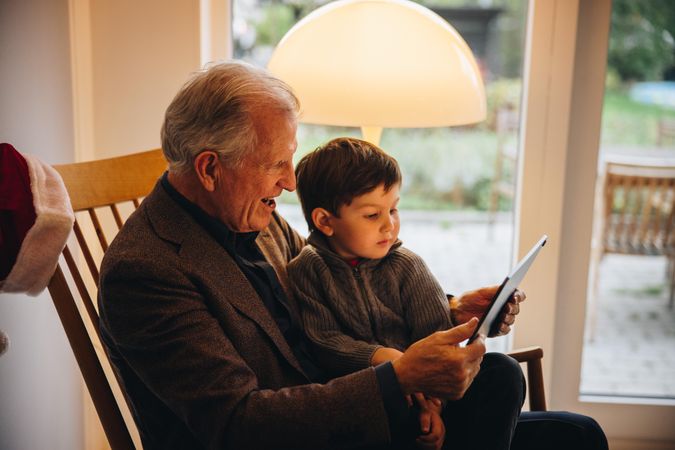 Mature man with a kid having a video call on digital tablet