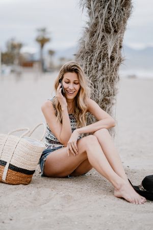 female talking on smartphone on beach