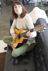 Female strumming guitar in living room of bright loft