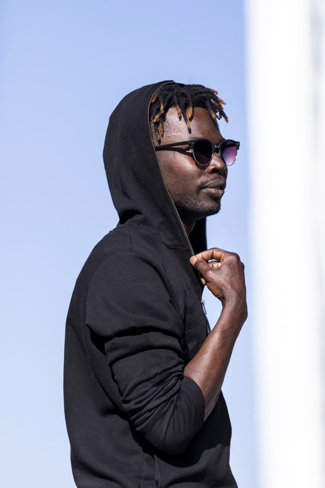 Black man wearing hoodie and sunglasses standing in the street