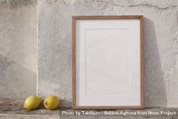 Minimal empty vertical wooden frame picture mockup against old textured wall in sunlight with fresh yellow lemons 5qkExo