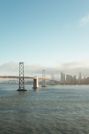 Long bridge construction over wavy water to city