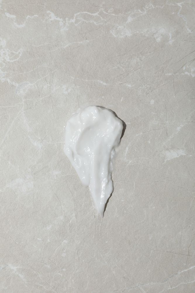 Cream drop on gray background, top view