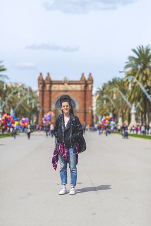 Front view of a young laughing hipster woman walking in a park in sunny day while looking away