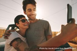 Couple pose for selfie holding each other with evening sun in the background 4ZdeO0