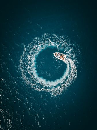 Aerial view of boat on water making spiral waves