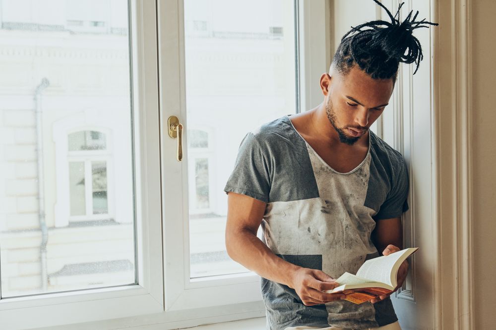 Black male standing by window and reading