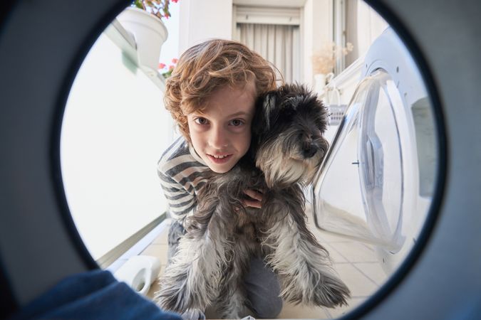 Curious boy with dog looking in washing machine
