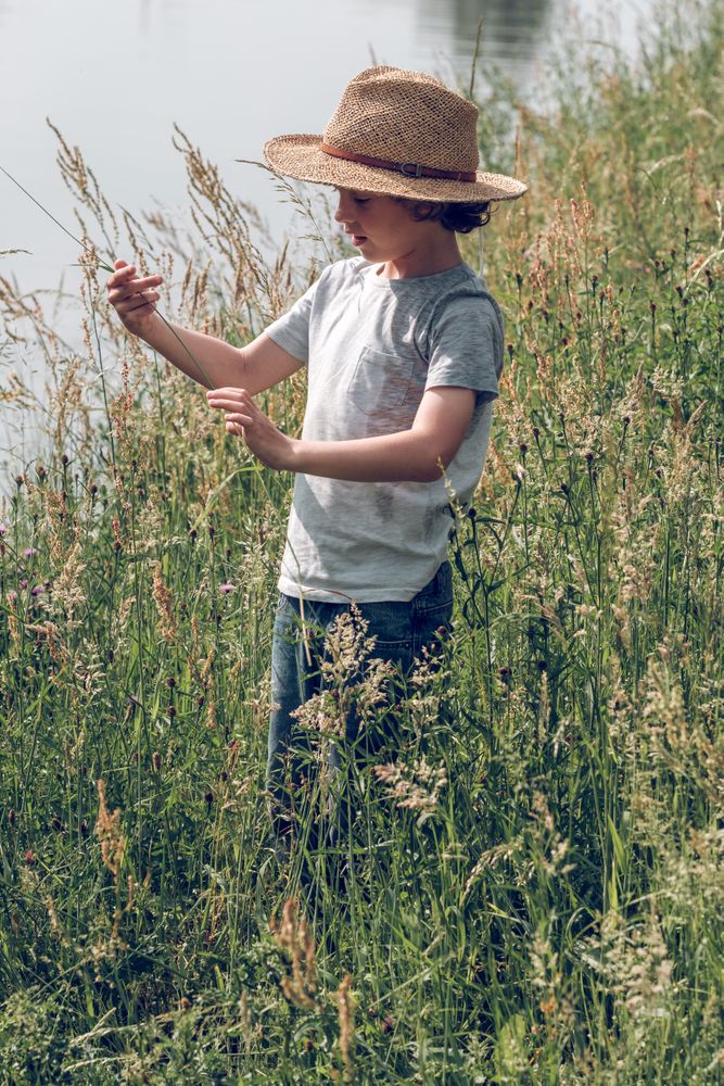 Boy among tall grass near river