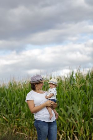 Adorable mother and child on hand enjoying and laughing in field