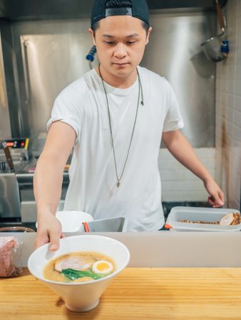 Young male decorating prepared Japanese dish