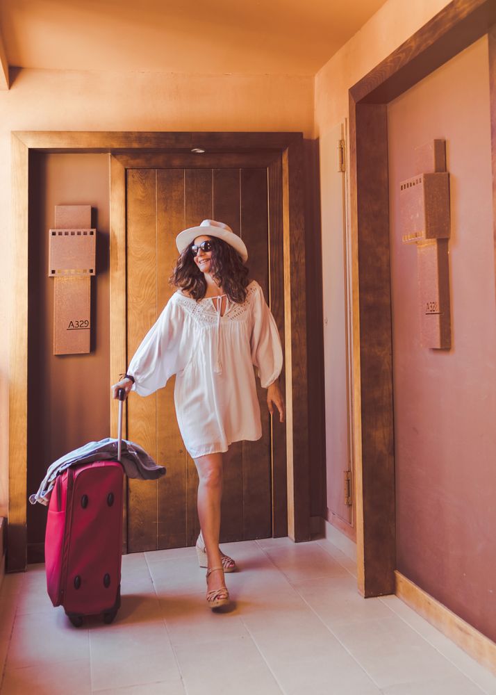 Happy lonely adult tourist going along hotel corridor