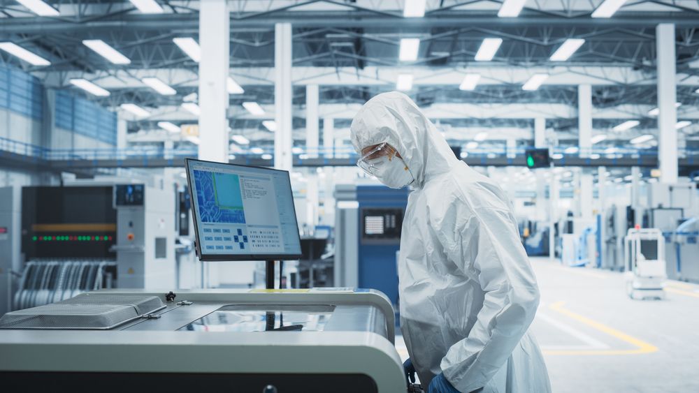 Scientist in hazmat protective suit working with computer in lab