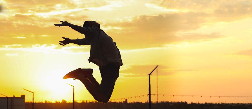 Photo of a young man in a jump. Happy man. Amazing sunset