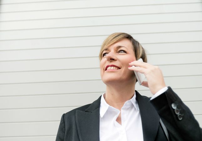 Businesswoman speaking on cellphone in front of wall