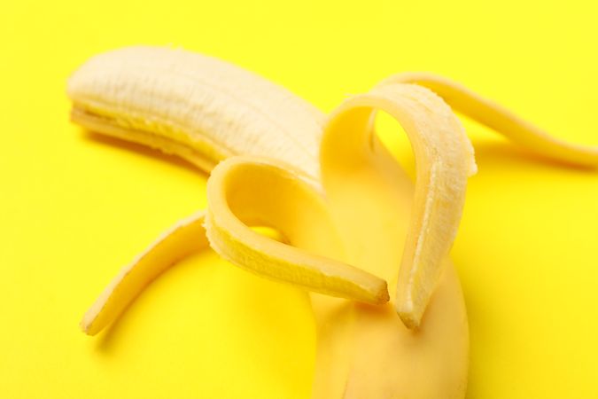 Heart made of banana on yellow background. Fresh fruit