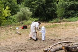 Unrecognizable beekeeper and child in costumes in countryside