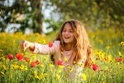 Happy girl playing with flowers in field