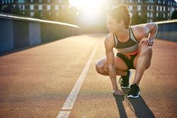 Fit woman crouching down on bridge practicing sprints