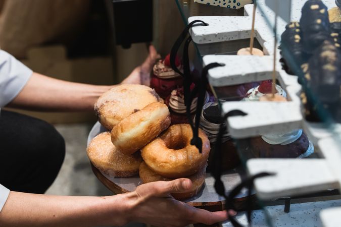 Crop cook with sweet desserts on tray in bakery