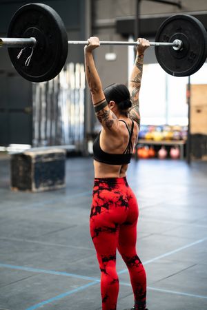 Back of woman completing jerk and clean with bar bell