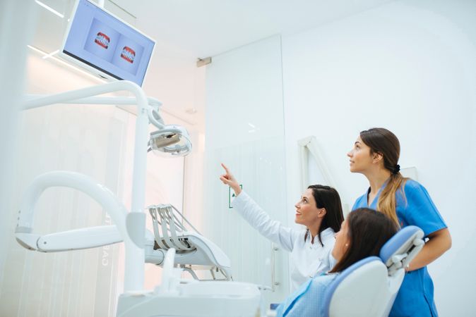 Dentist and assistant showing structure of teeth in picture to c