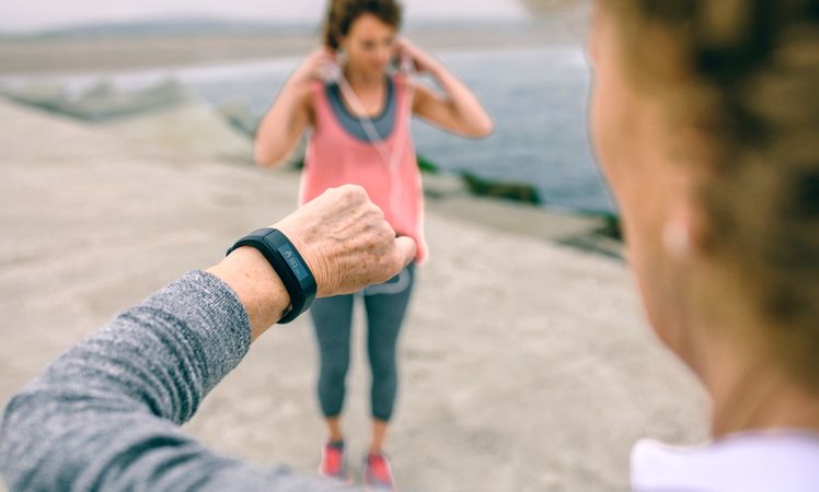 Older woman looking smart watch with female coach