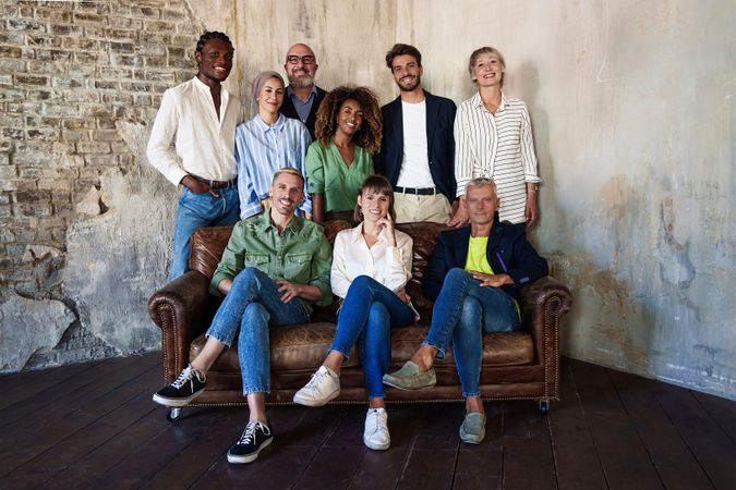 Portrait of multi-ethnic colleagues sitting on a sofa and standing together looking at the camera