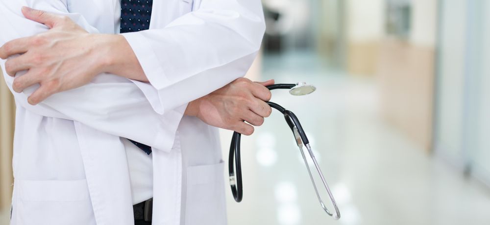 Body of doctor with stethoscope in bright hallway