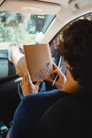 travel note book in hands of crop woman sitting on front seat of car in trip in Kings Canyon