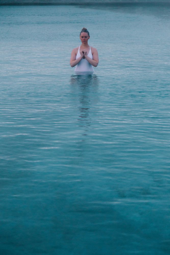 Woman in pool near sea and hills on shore