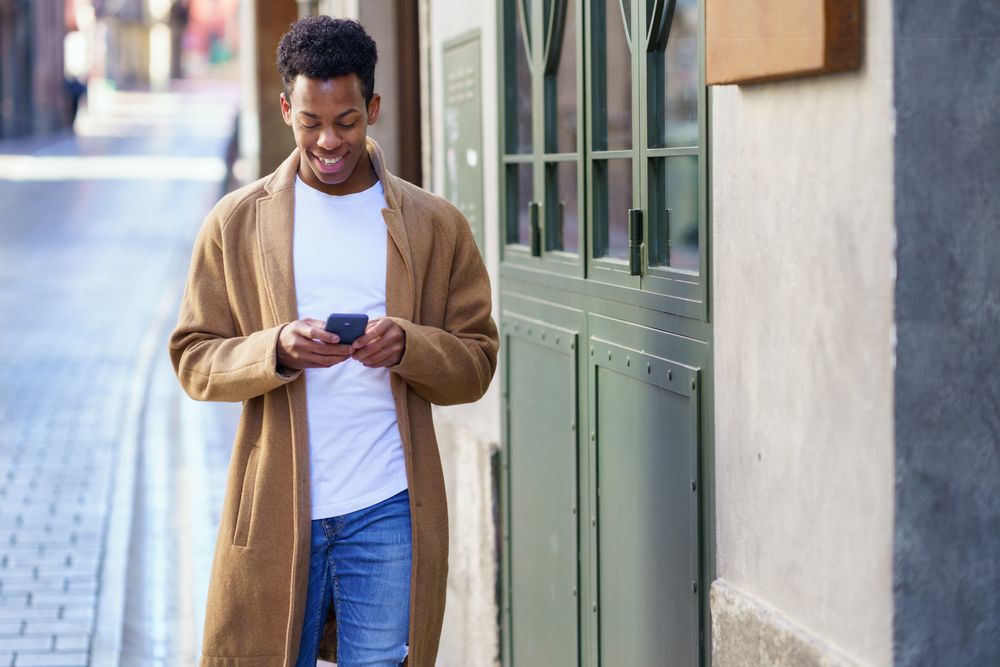 Cuban male texting on his phone while walking down the street