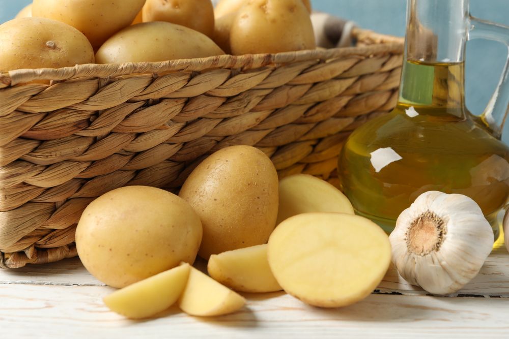 Side view of potatoes and garlic next to wicker basket