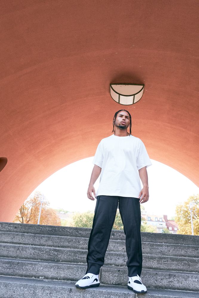 Trendy Black man posing near modern arch