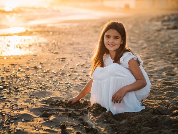 Adorable girl playing with sand on beach