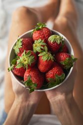 Crop woman with bowl of ripe strawberry