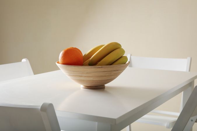 Bowl with oranges and bananas on table