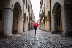 Tourist with umbrella walking at city street on rainy weather