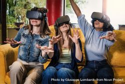 Three female friends in VR headsets on yellow sofa 4d87rL