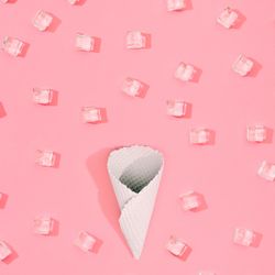 Cone with straw with ice cubes pattern on pastel pink background