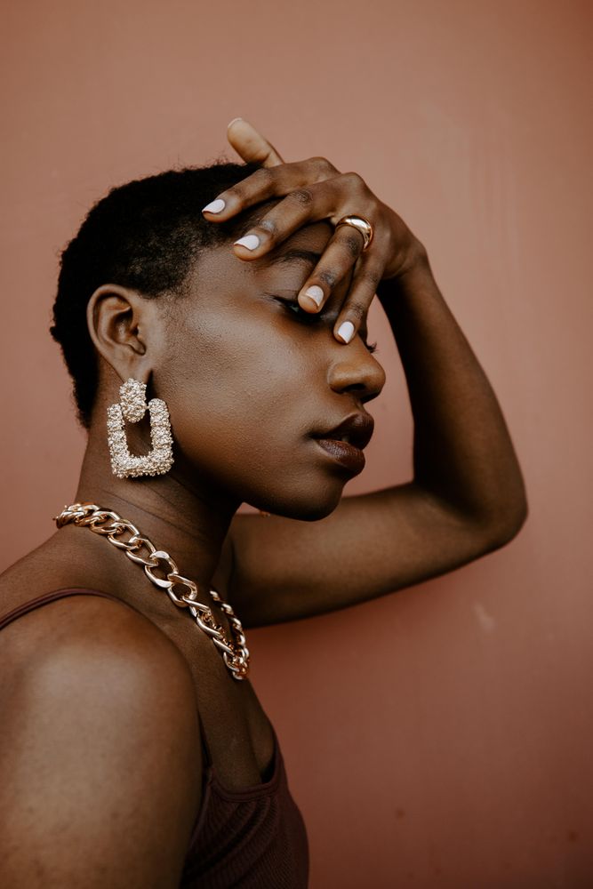 Side view of woman wearing gold necklace and gold ring and gold earring