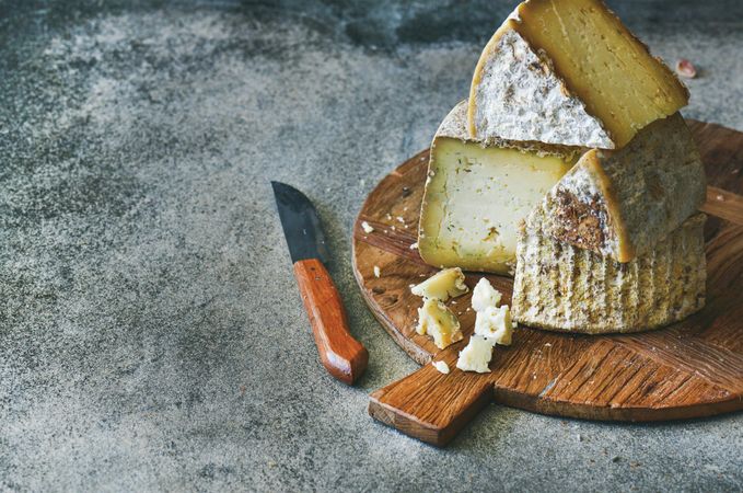 Wheel of cheese on wooden board, with knife