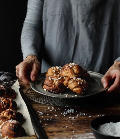 Crop female holding plate with cardamom buns